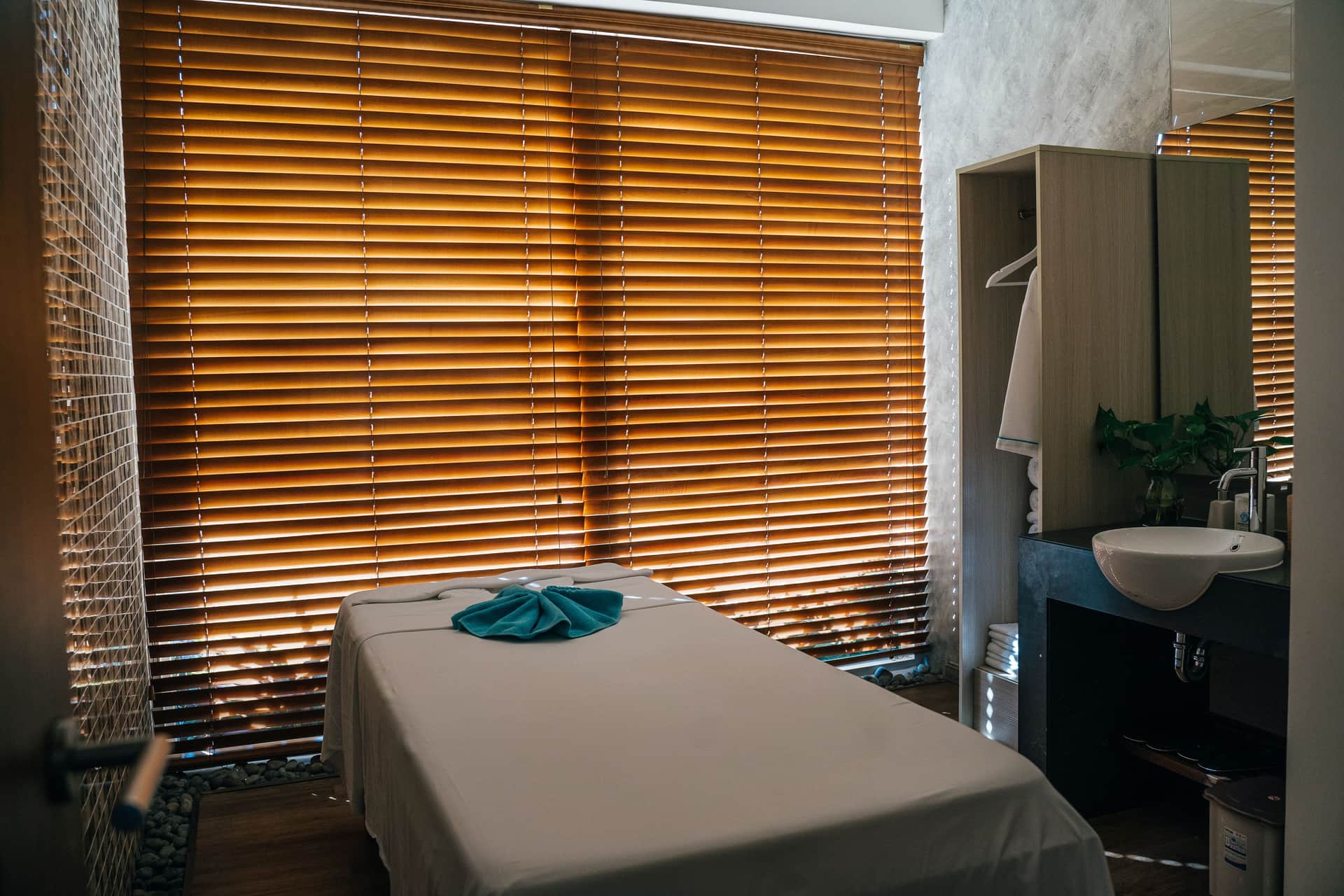 A quiet, softly lit treatment room set up with a massage table and folded linens.